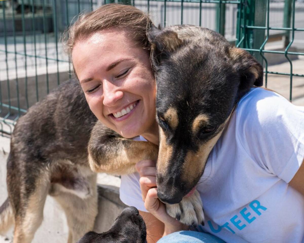 Young woman hugging a large dog at an animal shelter, both appearing happy and affectionate.